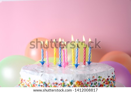 Birthday cake with burning candles and balloons on color background. Space for text