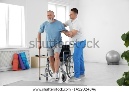 Professional physiotherapist working with senior patient in rehabilitation center Royalty-Free Stock Photo #1412024846