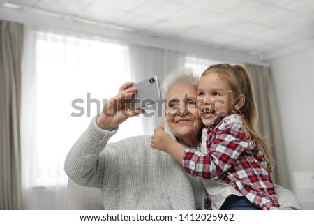 Cute girl and her grandmother taking selfie  at home