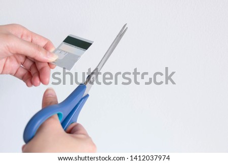 A person is cutting a credit card with scissors on white background with copy space; concept of prevent financial crises.