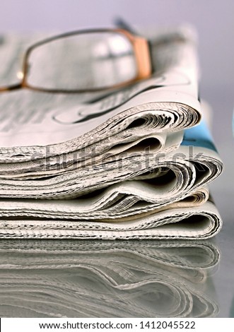 news paper sitting on a table with glasses no people stock photo
