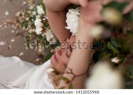 portrait of beautifull  middle aged woman posing in rose garden. wearing white wedding  dress