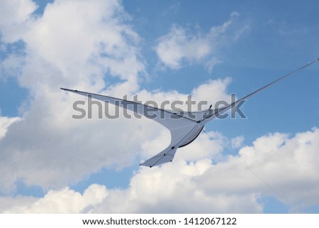 A kite in the form of a single large white bird. A kite in the sky among the clouds. Big white bird in the sky.