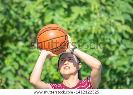 Leather basketball in hand of a woman wearing a watch Background blur tree in park.
