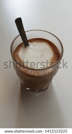 Latte in a glass with spoon on the table.