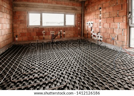 Details of underfloor heating and cooling during house construction. Plumbing details of flexible tubes and central heating system Royalty-Free Stock Photo #1412126186
