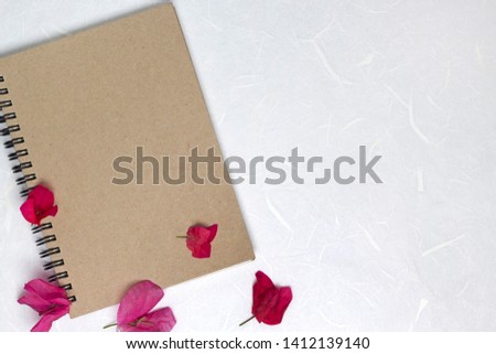 Craft cover notebook with pink flowers on white handmade fiber paper background. Flat lay, top view, copy space, mock up