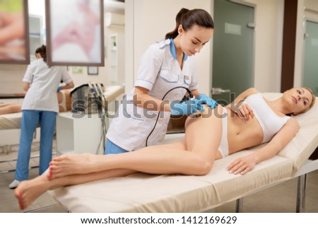 Massaging hips. Dark-haired massage specialist wearing the uniform massaging hips of client