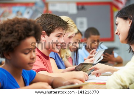 Pupils In Class Using Digital Tablet With Teacher Royalty-Free Stock Photo #141216970