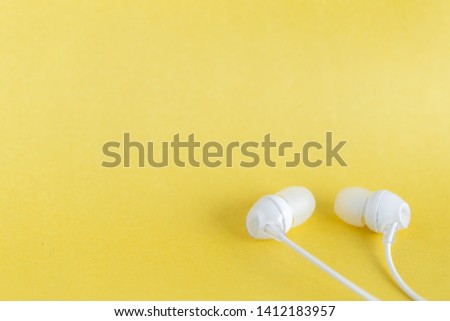 White earbuds on yellow pastel background with copy space for text
