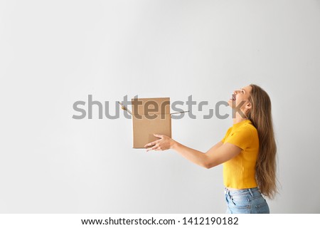 Young woman with open cardboard box on light background Royalty-Free Stock Photo #1412190182