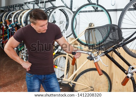 Male is choosing modern bicycle in the bike store. 