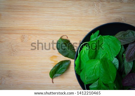 Green and red spinach in a dish on wooden background.
