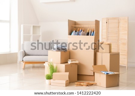 Wardrobe boxes with clothes and other things prepared for house moving in room