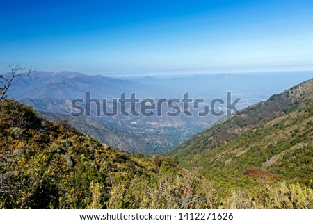 Mountain view of Andes and Aconcagua with green trees forest from Cerro la Campana, coastal mountain of Valparaiso, on clear day in La Campana National park in central Chile, South America
