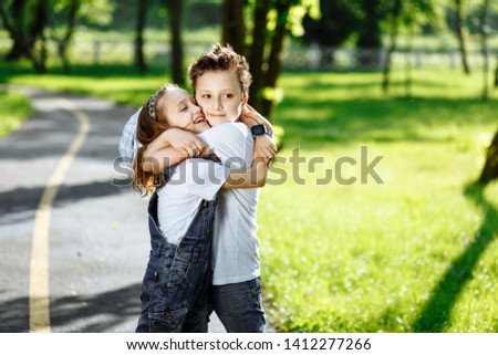 Picture of brother and sister having fun in the summer park on sunset. Cheerful children hugs and laughing. Little girl and boy playing outdoors, best friends, happy family, love and happiness concept