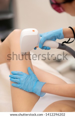Skinny client. Skinny client wearing underwear lying and having laser depilation in beauty salon