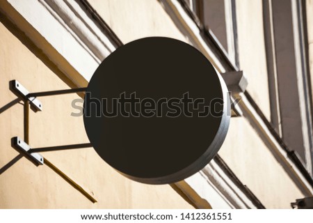 All black round signboard template on a street.