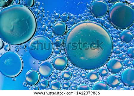 Vivid blue psychedelic abstract formed by oil droplets floating on water