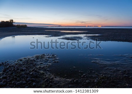 Reflections of the sunset light in the calm water of the sea bay.