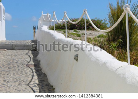 Mediterranean lanscape with rope fence and south plants. Narrow street of Santorini.