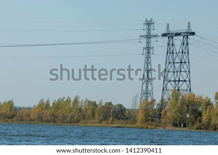Autumn landscape, river, energy pillars, High voltage pole on blue sky background