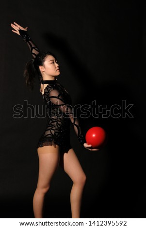 Japanese beautiful young fit athlete woman with red color ball rhythmic gymnastics exercise in studio black background