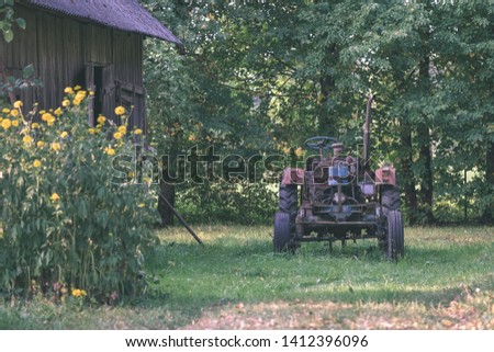 old tractor with rubber tires in green countryside yard in green summer time - vintage retro film look