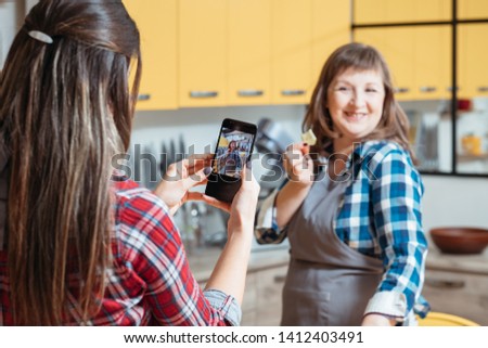 Healthy dieting eating habit. Two women mother daughter in kitchen cooking taking smartphone pictures. Culinary blogger