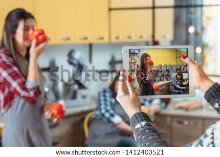 Mother daughter in kitchen. Woman hands with tablet taking pictures of blogging family. Cooking leisure lifestyle hobby.