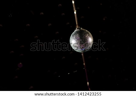 shiny disco ball with reflective chips hanging from a rod, isolated on black background