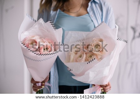 Very nice young woman holding two big and beautiful mono bouquets of fresh tender pink ranunculus flowers, cropped photo, bouquet close up