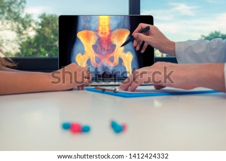 Doctor showing a x-ray of hips and spine with pain on a laptop to a woman patient. 