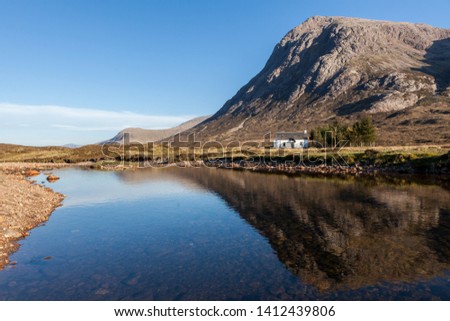 Reflections of a cottage with hill behind in Glen Coe Scotland