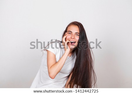 Close up portrait of a pretty young brunette schoolgirl smiling charmingly, isolated on white wall background