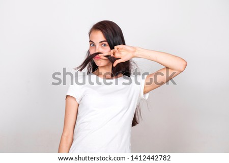 Young beautiful girl with a mustache from their hair in the studio on a white background