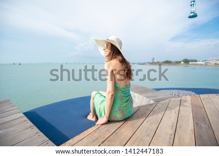 Beautiful woman in white hat is sitting on the hotel with the beach 
