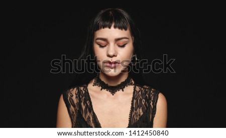 Woman with fashion piercing on lips isolated on black background. Portrait of a young gothic woman with eyes closed.