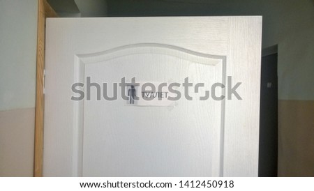 Texture, wallpaper, background, image of a white wooden door with the inscription "Toilet" pasted on the adhesive tape in Russian and an adjacent picture denoting a man.