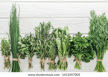 top view of various green herbs on white wooden table