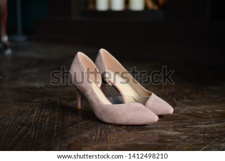 beige high-heeled shoes elegant leather women's shoes on a wooden background light glossy heel shoes on a pillow of straw.