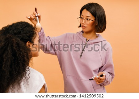 Backstage of photo shooting. Makeup artist corrects makeover on model.