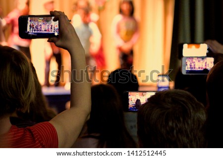 A sea of parents’ cell phones are held high to record their children’s performance in a school play. Royalty-Free Stock Photo #1412512445