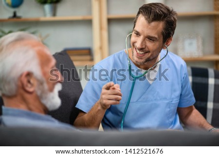 Happy doctor gesturing while talking to a senior patient during a home visit. 