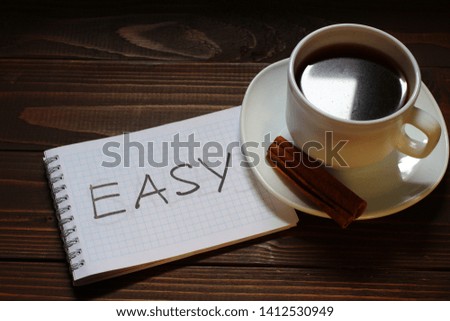 Easy inscription and word in a notebook near a cup of coffee