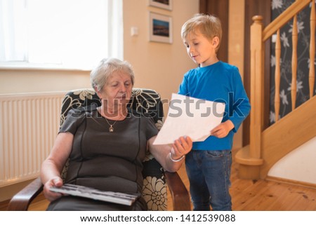 Grandson shows grandmother  picture with painted picture by himself