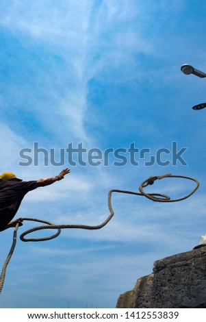 Man is throwing mooring lasso rope to the pole on pier at Koh Is Chang Island, Chonburi Thailand. Royalty-Free Stock Photo #1412553839