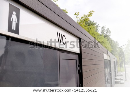 public toilet in city park landscape closeup exterior view of wc men sign on restroom facade and entrance side of lavatory building outdoor authentic lifestyle background concept