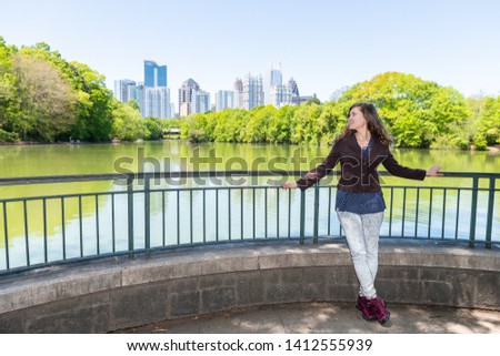 Atlanta, Georgia skyline in Piedmont Park view green trees urban city skyscrapers with happy young business woman girl