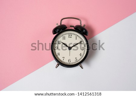
Retro alarm clock in black on a pink and white background. Good morning. Deadline